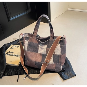 Detail of vintage patchwork denim tote bag with adjustable wide strap on leather jacket