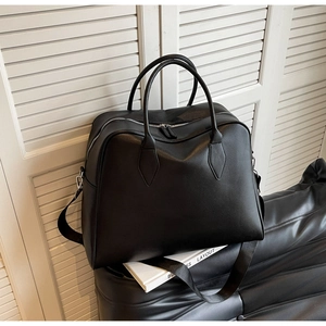 Detail shot of black pebbled leather texture on a high-capacity tote bag with metal zipper