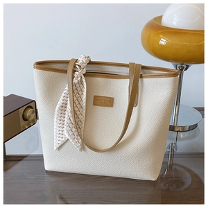 Close-up of white lychee leather tote bag with brown straps and geometric silk scarf