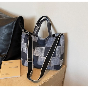 Detail of patchwork denim tote bag with frayed edges and wide shoulder strap