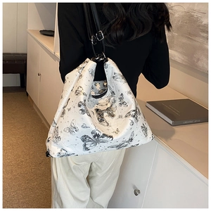 Detail of white butterfly print hobo bag with silver bow buckle and black strap