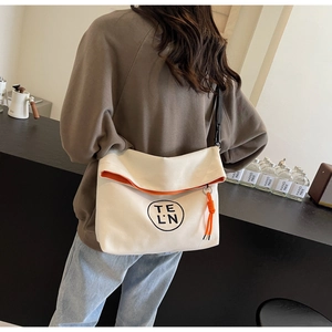 Detail of canvas tote bag with orange trim and logo in a stylish lifestyle setting