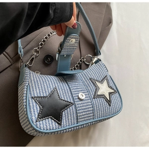 Détail du sac tissé bleu et blanc avec patchs étoiles et bandoulière chaîne argentée