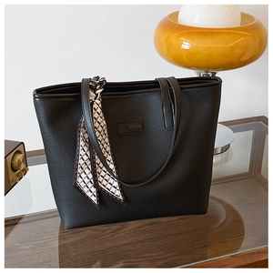 Detail of black pebbled leather tote bag with geometric silk scarf and embossed logo