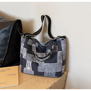 Detailed patchwork denim tote bag with frayed edges on stone base in vintage setting