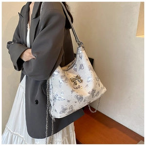 Close-up of butterfly print tote bag featuring silver chain straps and metallic butterfly charm