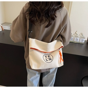 Detail of off-white canvas tote bag with orange lining and adjustable shoulder strap