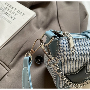 Détail du sac tressé bleu clair avec chaîne argentée et écusson étoile noire