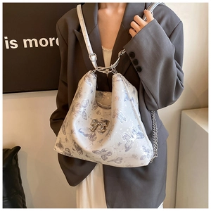 Detail of printed butterfly tote with silver metallic bow on model in grey oversized blazer