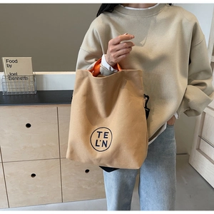 Close-up of large canvas tote bag with contrast orange handles and logo print