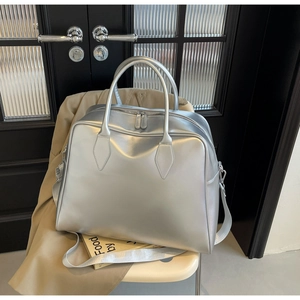 Detail of silver metallic tote bag with top handles and adjustable strap on a chair