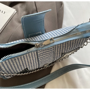 Détail de la texture tissée bleu et blanc avec rabat en cuir bleu clair et zip argenté
