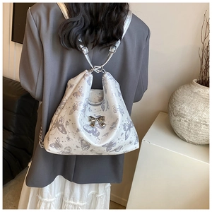 Detail of white tote bag with purple butterfly print and silver metallic bow accent