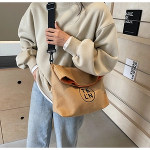 Lifestyle shot of khaki large capacity canvas tote with orange lining and black strap