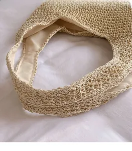 Detail of the woven straw tote bag handles with comfortable wide-strap braiding and soft lining