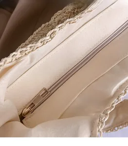 Close-up of smooth gold metal zipper and beige fabric lining on a woven tote bag