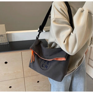 Close-up of gray canvas tote bag featuring orange lining and embroidered logo detail