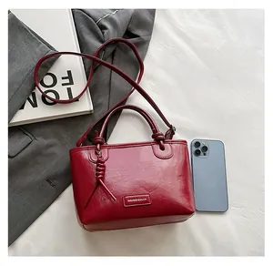 Vue macro d'un petit sac seau bordeaux montrant sa taille comparée à un smartphone