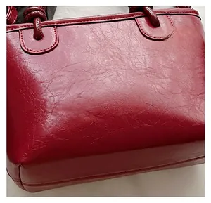 Gros plan détaillé sur le cuir ciré brillant bordeaux et les coutures de ce sac seau élégant