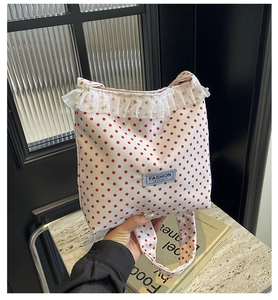 Detail of white nylon bucket bag with red polka dots, lace trim and pearl accents
