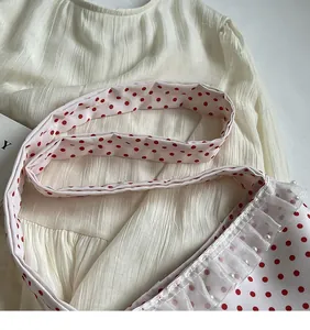 Detail view of red polka dot nylon bucket bag with pearl lace trim and wide shoulder strap