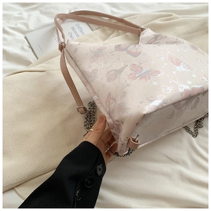Detail of pink butterfly tote bag with star patterns and silver metal chain strap