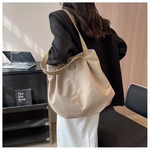 Side view of beige nylon tote bag with BAOBAO label on a person's shoulder