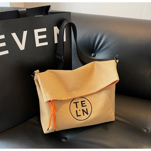 Detail of khaki canvas tote with orange lining, black shoulder strap and logo print