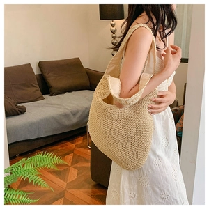 Detail of hand-woven straw tote bag with wide shoulder strap and fabric lining