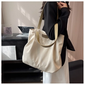Detail of a large beige nylon tote bag with contrasting green shoulder straps for work