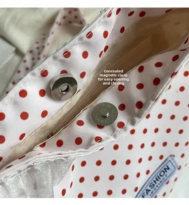 Detail of invisible magnetic buckle and zipper closure on red polka dot bucket bag
