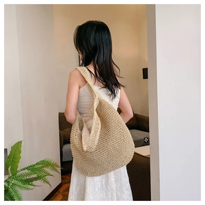 Detail of a large straw woven hobo bag with wide shoulder strap for summer vacation use