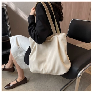 Chic cream nylon tote bag styled with a professional black blazer for business commute