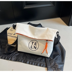 Detail of white canvas tote bag with orange lining and logo on black leather jacket