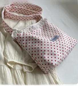Detail of red polka dot fabric bag with lace trim and Fashion Instinct label