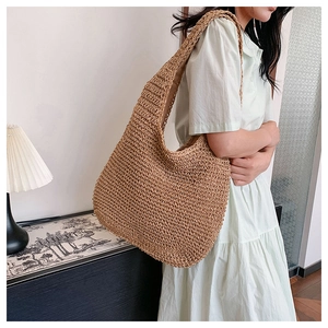Detail of the woven straw hobo bag showing the natural texture and wide shoulder strap