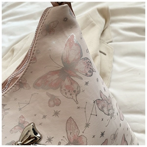 Detail of pink woven tote bag with butterfly star prints and silver butterfly charm