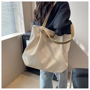 Side view of large cream canvas tote bag with khaki strap on female shoulder