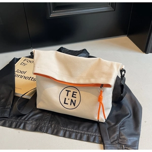 Detail of canvas tote bag with logo on black leather jacket and orange lining accents