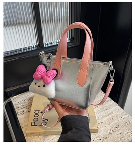 Close-up of metallic silver handbag with pink handle and plush cloud charm accessory