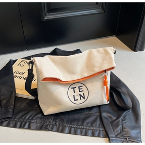 Detail view of off-white canvas tote bag with orange lining on a black leather jacket