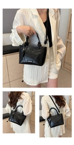 Gros plan d'un sac seau noir vintage avec logo argenté et doubles poignées de main