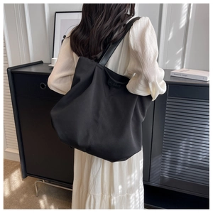 Close-up of matte black canvas tote bag with embossed BUDBAG logo and textured fabric