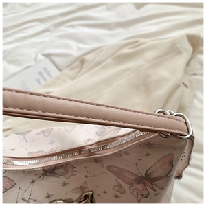 Close-up of butterfly print and neat stitching on light pink PU leather shoulder bag