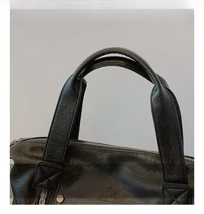Detailed view of black litchi pattern leather tote with reinforced X-stitched handles