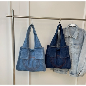 Close-up of denim tote bags in light and dark blue with red circular embroidery detail