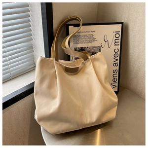 Detail showing the RUDBAG leather label and handles on a beige canvas tote bag