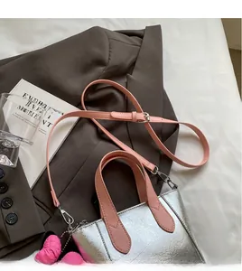 Detail of silver metallic tote bag with pink leather handles and adjustable shoulder strap