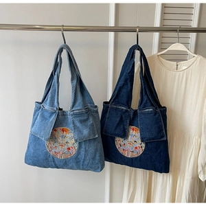 Détails de la broderie de dragon sur les sacs cabas en denim bleu clair et foncé