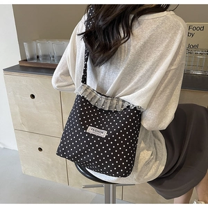 Dettaglio borsa a secchiello a pois con bordo in pizzo e perle sulla tracolla della borsa